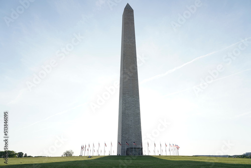 Washington monument and american flag on white and blue sky (District of Columbia, USA)