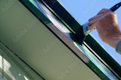 A top coat of paint is being applied to a barge board, the dark green will cover the pink undercoat or primer