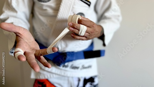 A male brazilian jiu-jitsu athlete is getting ready to train by taping his fingers. photo