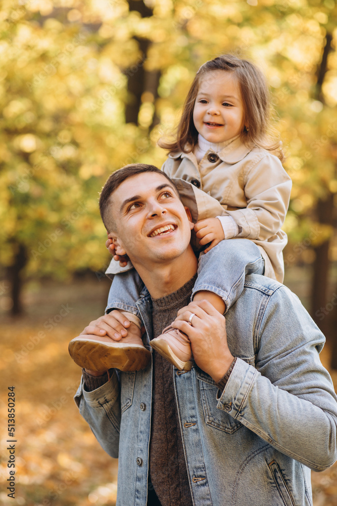 Fototapeta premium Happy dad and little daughter walking in autumn park, father's day concept