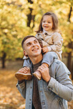 Happy dad and little daughter walking in autumn park, father's day concept