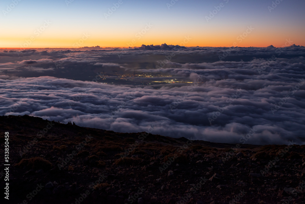 haleakala twilight above the clouds and city lights below