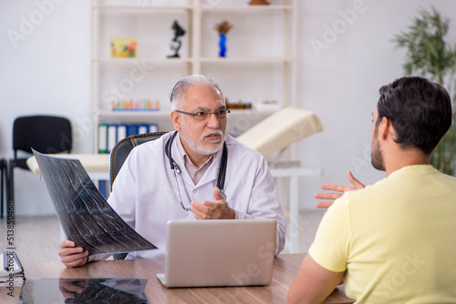 Young male doctor visiting old male doctor radiologist