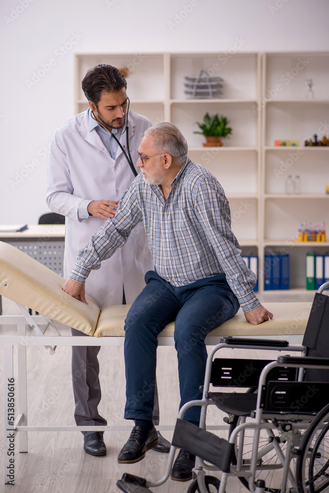Old man in wheelchair visiting young male doctor Old man in wheelchair visiting young male doctor