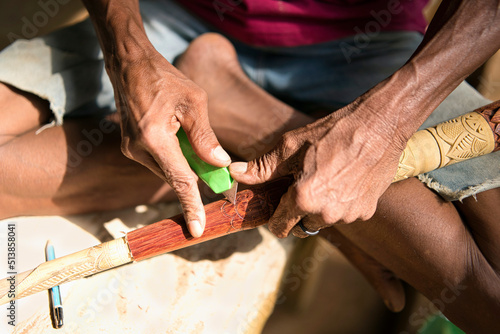 Φωτογραφία Hand of an indigenous person carving on the surface of the blowpipe or sumpit