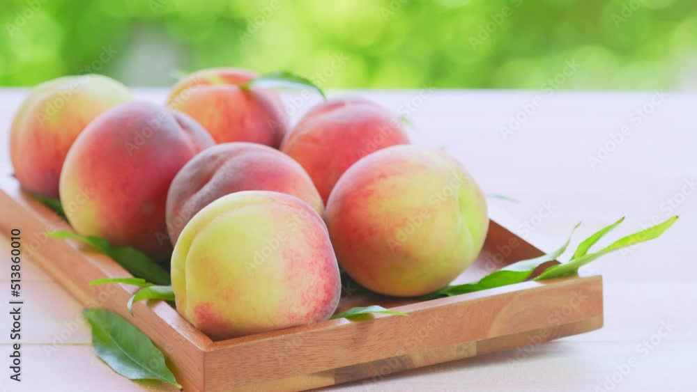 Fresh Sweet Peach on green bokeh background, Pink and yellow Peach fruit with leaf on wooden plate. 