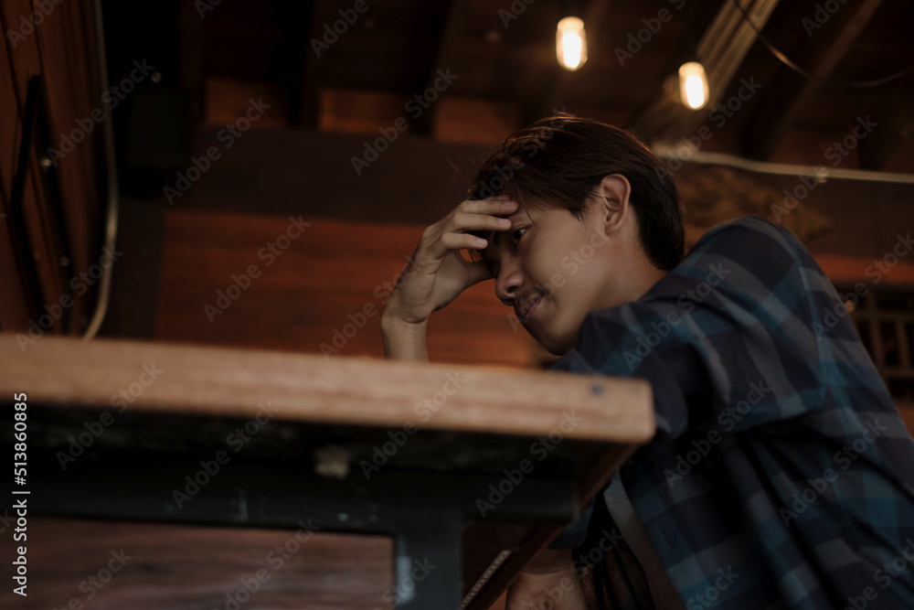 A young Asian man sits at the bar counter in a restaurant to relax A young Asian man sits at the bar counter in a restaurant to relax