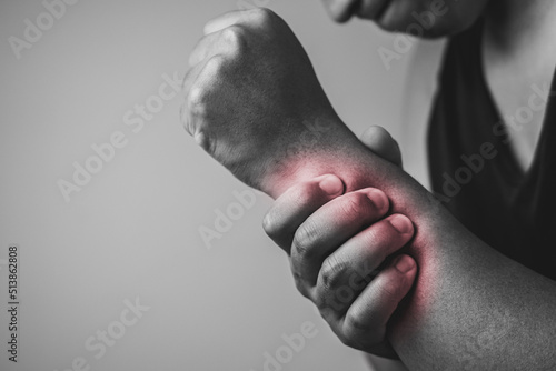 Elbow injury from tennis and golf. The man uses fingers to massage his arm. Pain symptom area is shown with red color. Healthcare knowledge. Medium close up shot with copy space. Black and white tone.