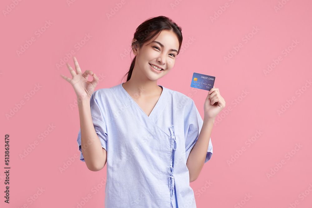 Beautiful Young Asian Woman Patient Showing Credit card on pink background, Insurance card concept. Beautiful Young Asian Woman Patient Showing Credit card on pink background, Insurance card concept.