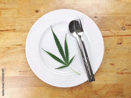 cannabis leaves in white plate on wooden table