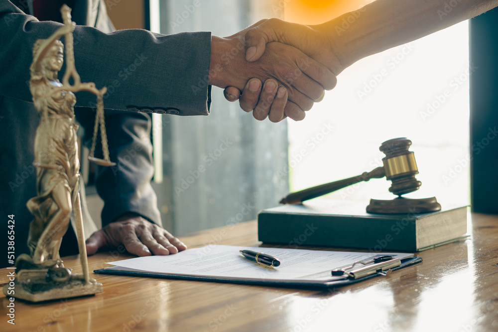Businessmen shake hands with lawyers to seal a deal with a partner lawyer or a lawyer who is discussing a contract agreement. with a hammer and the goddess of justice Businessmen shake hands with lawyers to seal a deal with a partner lawyer or a lawyer who is discussing a contract agreement. with a hammer and the goddess of justice