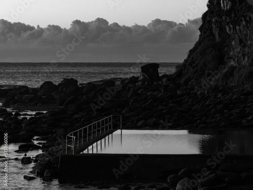 Early morning at the seapool with rocks and headland in monochrome photo