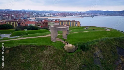 unique revealing drone shoot of 
Elogio del horizonte  scuplture in Cimadevilla in Gijón where we see the bay and the sea and the mountain of the city in the background during a quiet cloudy afternoon photo