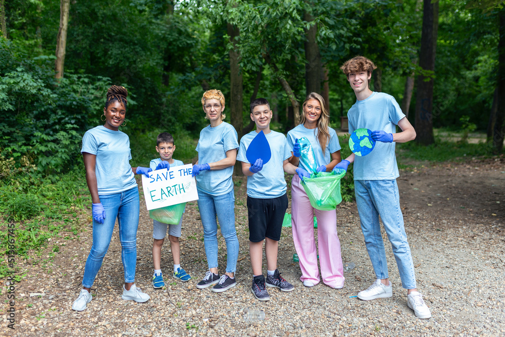Obraz premium Diverse Group of People Picking Up Trash in The Park Volunteer Community Service. Happy international volunteers holding placard with 'Save the Earth' message.