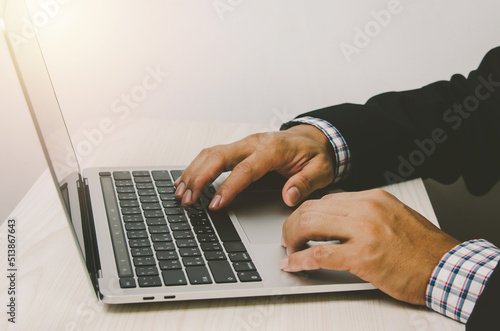 Man hands working on laptop keyboards, searching the Internet or shopping online or sending emails at their desks.