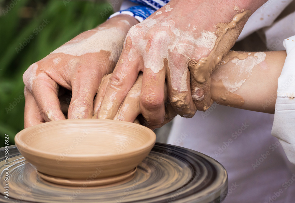 Hands of the master help to work on the potter's wheel