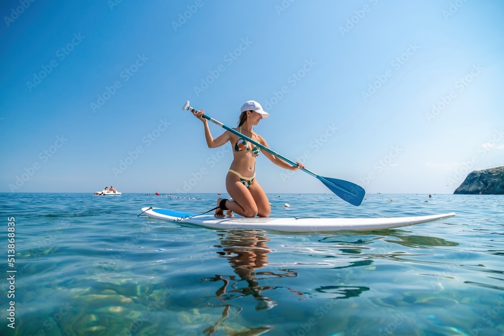 SUP Stand up paddle board. Young woman sailing on beautiful calm sea with crystal clear water. The concept of an summer holidays vacation travel, relax, active and healthy life in harmony with nature.