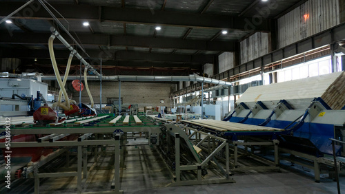 Woodworking production with computerized automatic equipment. The boards are moving along a conveyor belt in the factory