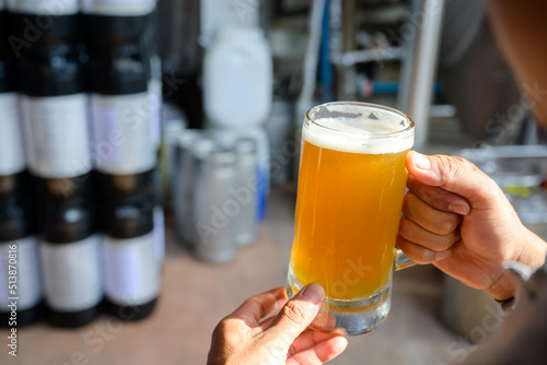 Male craft brewer holding beer mug at brewery Small Business and the Beer Industry golden yellow beer mug in warehouse