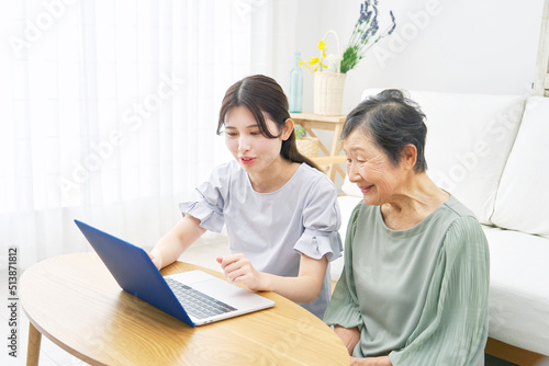 リビングでノートパソコンを使う孫と祖母