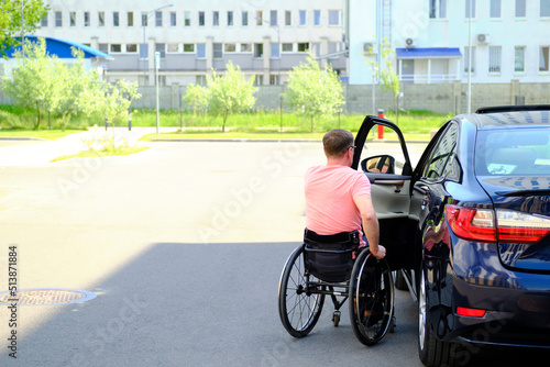 a man in a wheelchair closes the door of his car, driver with disability © Alex