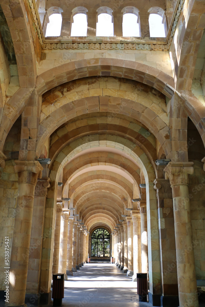 Gallery of columns and arches, built of light stone, ending with a window, vertical