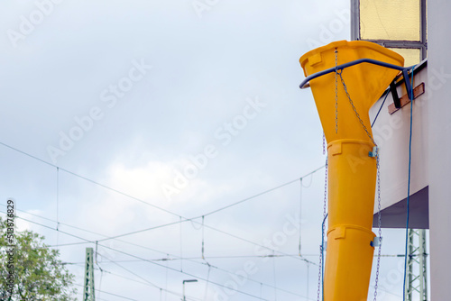 Yellow rubble chute or rubble slide at facade of old white house helps with renovation and refurbishment of old property for clean rubble removal and waste removal into container for construction site