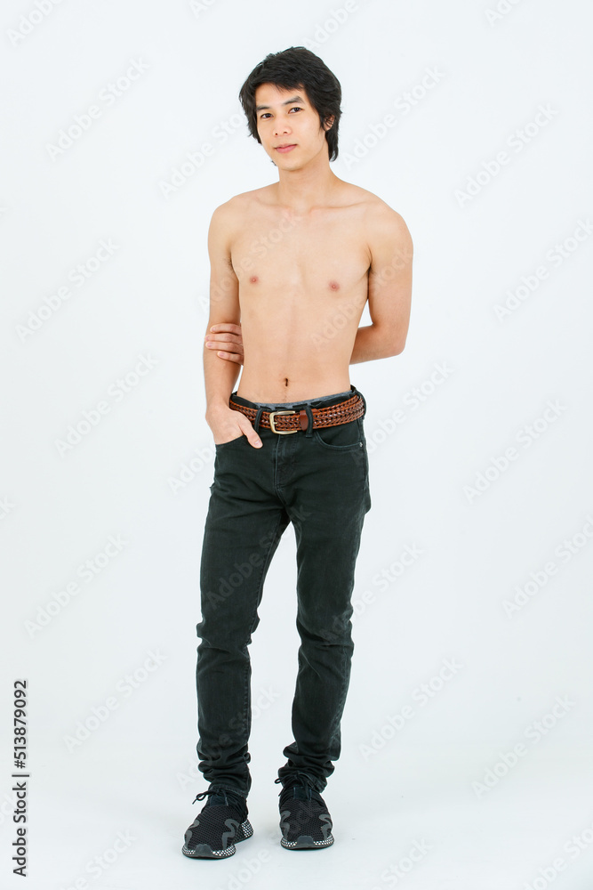 Portrait isolated cutout studio shot of Asian young handsome confident slim  thin muscular shirtless teenager male model standing posing holding hand in  denim jeans pants pocket on white background Stock Photo