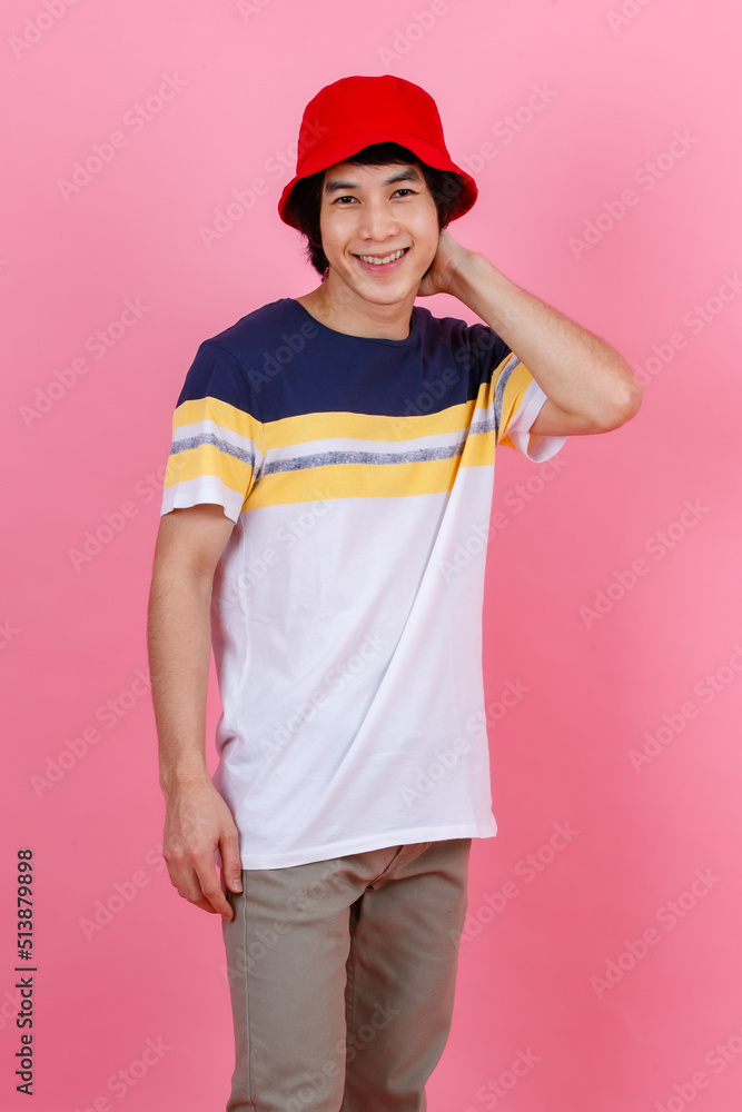 Portrait studio shot of Asian young handsome urban teenager fashion male model in street style outfit t shirt sport beige pants and red bucket hat standing posing look at camera on pink background Portrait studio shot of Asian young handsome urban teenager fashion male model in street style outfit t shirt sport beige pants and red bucket hat standing posing look at camera on pink background