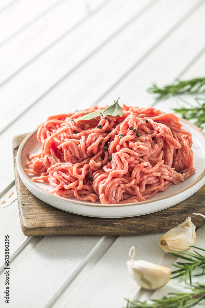 Fresh Raw Beef Minced Meat with herbs and rosemary on wooden board on a light background, banner, menu, recipe place for text, top view, Fresh Raw Beef Minced Meat with herbs and rosemary on wooden board on a light background, banner, menu, recipe place for text, top view,