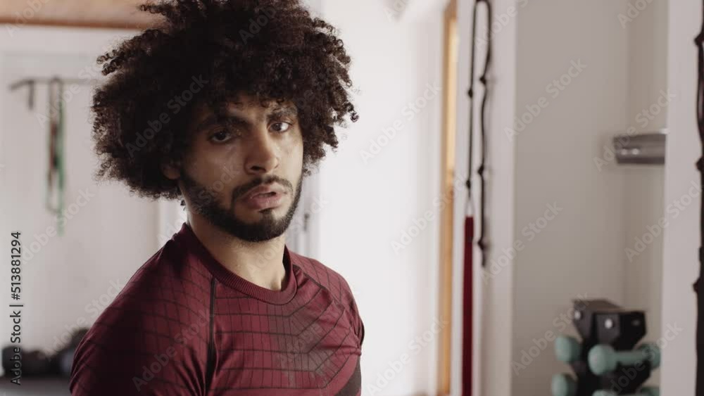 Portrait of young adult middle Eastern male standing up after exercise and looking seriously at camera at an indoor fitness gym Portrait of young adult middle Eastern male standing up after exercise and looking seriously at camera at an indoor fitness gym
