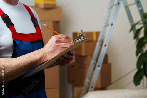Man mover in uniform making notes on clipboard, close up