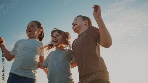 group of kids team hugging a jumping and rejoicing outdoors. happy family teamwork kid dream lifestyle concept. family children sisters brothers have fun hugging in the park in nature © ibragimova