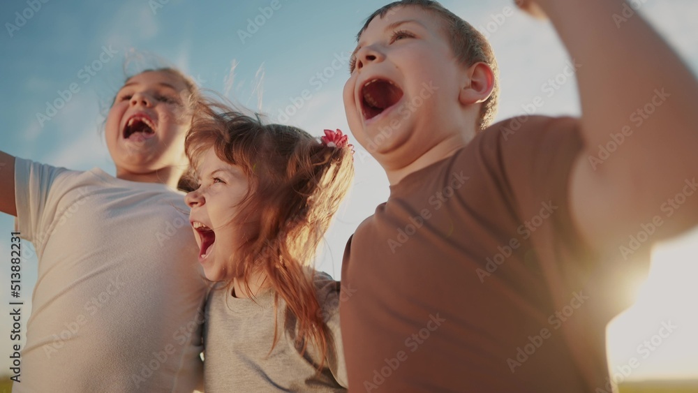 Fototapeta premium group of kids team hugging a jumping and rejoicing outdoors. happy family teamwork kid dream concept. family children sisters brothers have sun fun hugging in the park in nature