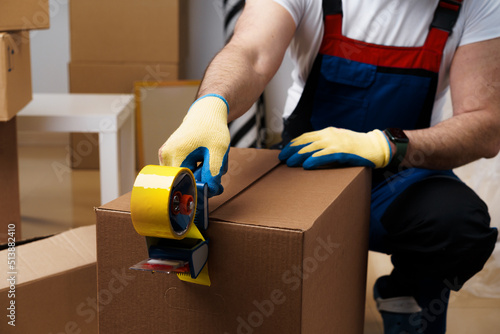 Man mover in uniform packing boxes with scotch tape photo