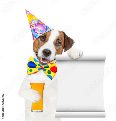 Happy Jack russell terrier puppy wearing tie bow and party hat holds  beer and empty list. isolated on white background © Ermolaev Alexandr
