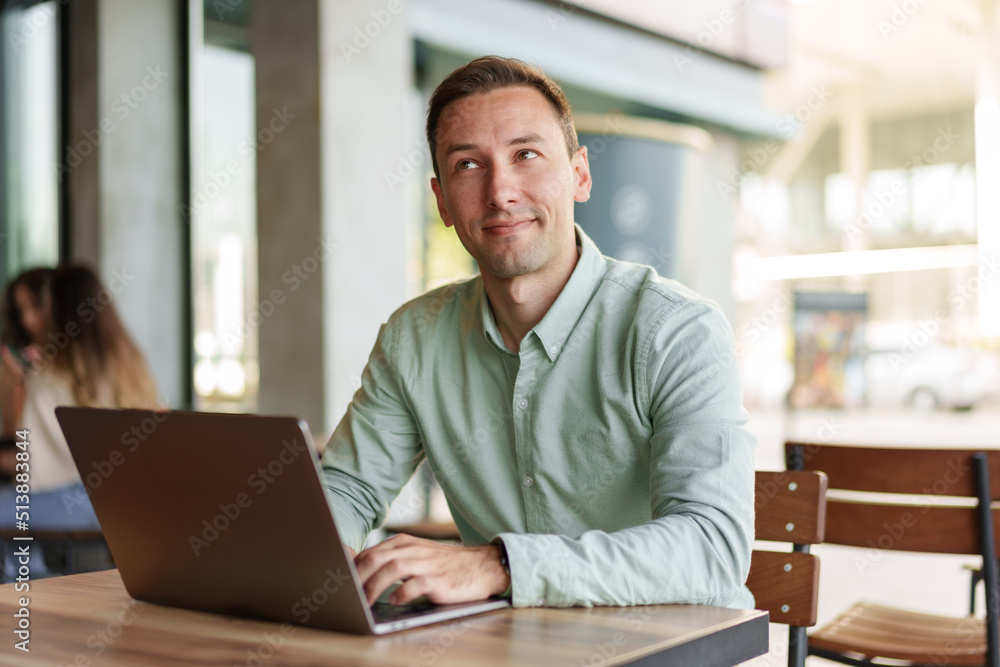 Young businessman sitting in cafe working with laptop computer Young businessman sitting in cafe working with laptop computer