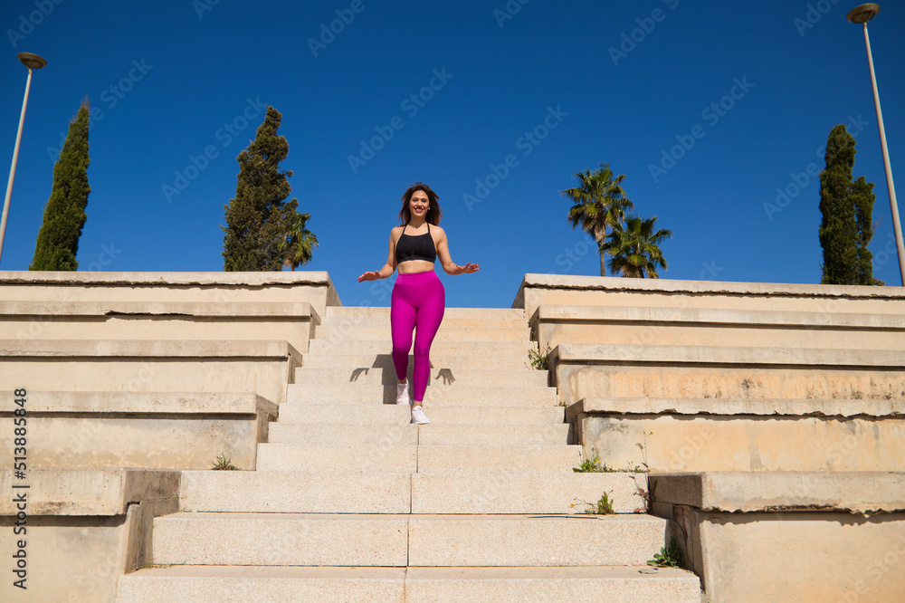 Beautiful, mature woman walking down the stairs in the park where she practices different sports. The woman is running down the stairs. Concept of health and well-being. Sport