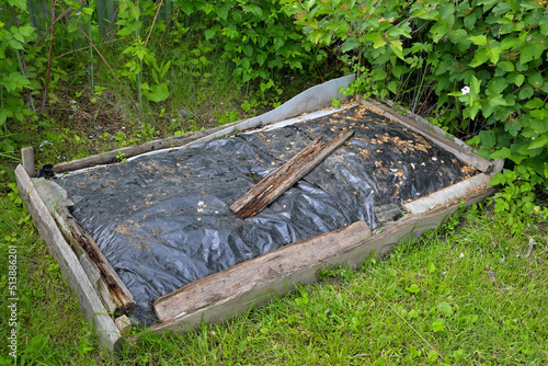A primitive compost pit under a plastic awning on a summer day