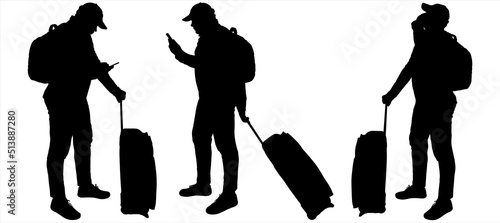 Tourists with backpacks and suitcases on wheels. A young guy in a cap stands sideways and talks on a mobile phone. Two guys separately communicate with each other. They send text messages on the phone