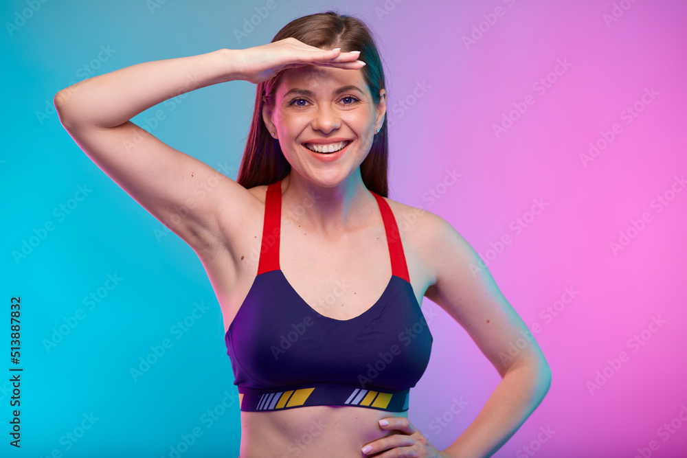 Fototapeta premium Sporty coach trainer woman in fitness sportswear looking for, with hand on forehead. Female fitness portrait isolated on neon multicolor background.
