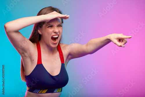 Strict sporty coach woman in fitness sportswear looking for new new aspiring athletes. Female fitness portrait isolated on neon multicolor background.