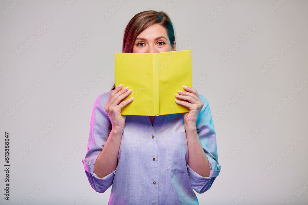Smiling woman cover her face with yellow book. isolated female portrait on gray background