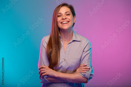 Smiling woman with arms crossed portrait in neon lights. Businesswoman isolated on neon multicolored background.