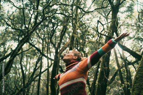 Happy adult woman smile and open arms to embrace beautiful nature forest around her. Concept of green ambient and sustainable tourism travel people. Earth\'s day and love for woods concept