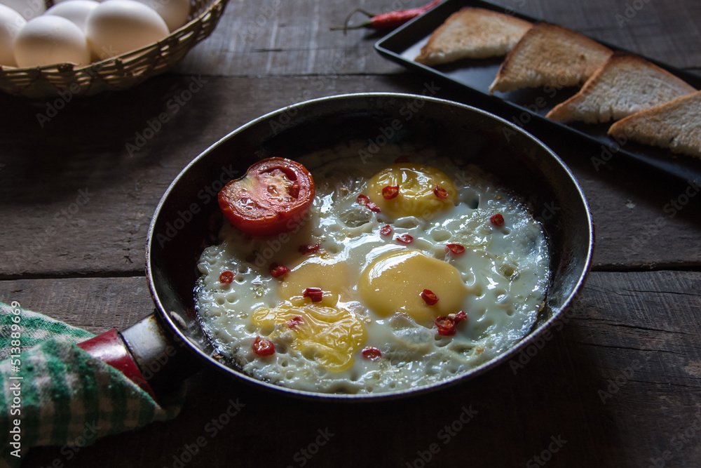 Breakfast item fried eggs in a frying pan on a background. Close up, selective focus. Breakfast item fried eggs in a frying pan on a background. Close up, selective focus.