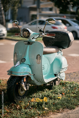 Close up of a vintage light blue retro moped parked on the street.
