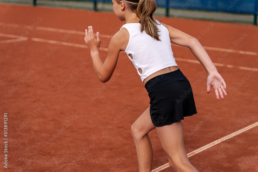 Tennis player warming up on tennis court. Girl running on the court