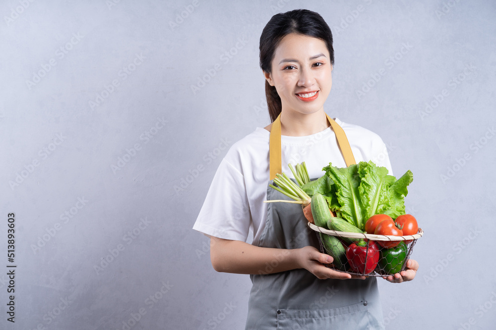 Young Asian woman holding vegetables on background Young Asian woman holding vegetables on background