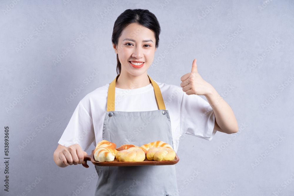 Young Asian woman holding bread on background Young Asian woman holding bread on background